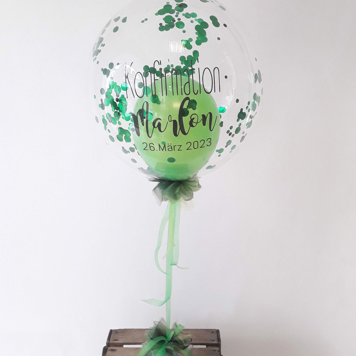 Bubble-Ballon mit grünem Konfetti, innliegendem grünen Ballon, Schleife, transparenter Aufdruck 'Konfirmation Marlon 26. März 2023'