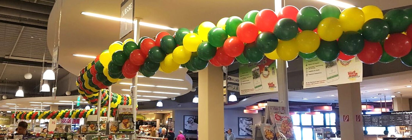 rot-gelb-grüne Ballongirlande über dem Ausgang mit Kassen eines Supermarktes