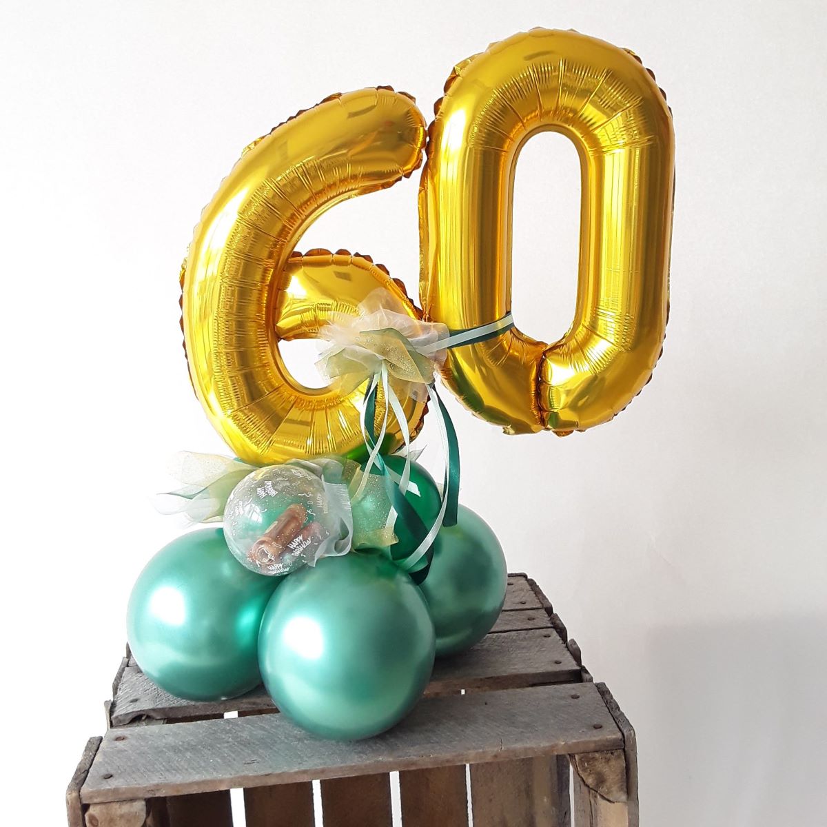Ballondekoration mit goldenen Zahlenballons '60' auf grünem Ballonfuß und integriertem Geldgeschenk in einer kleinen transparenten Kugel gefüllt mit Geldscheinen