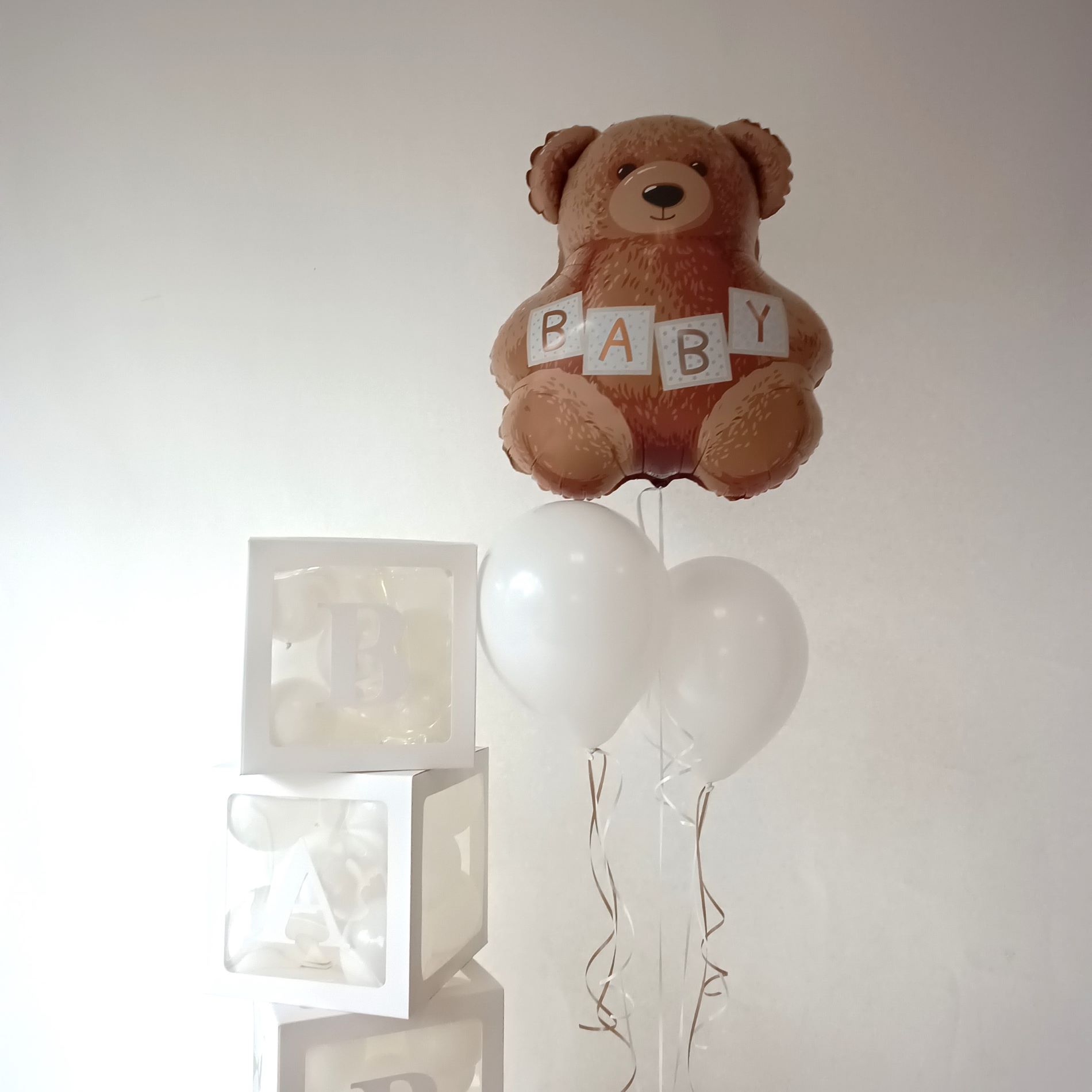 Ballondekoration mit schwebendem Folienballon in Bärenform mit BABY-Aufdruck, zwei weißen Heliumballons und vier weißen transparenten Baby-Boxen mit kleinen Ballons gefüllt2