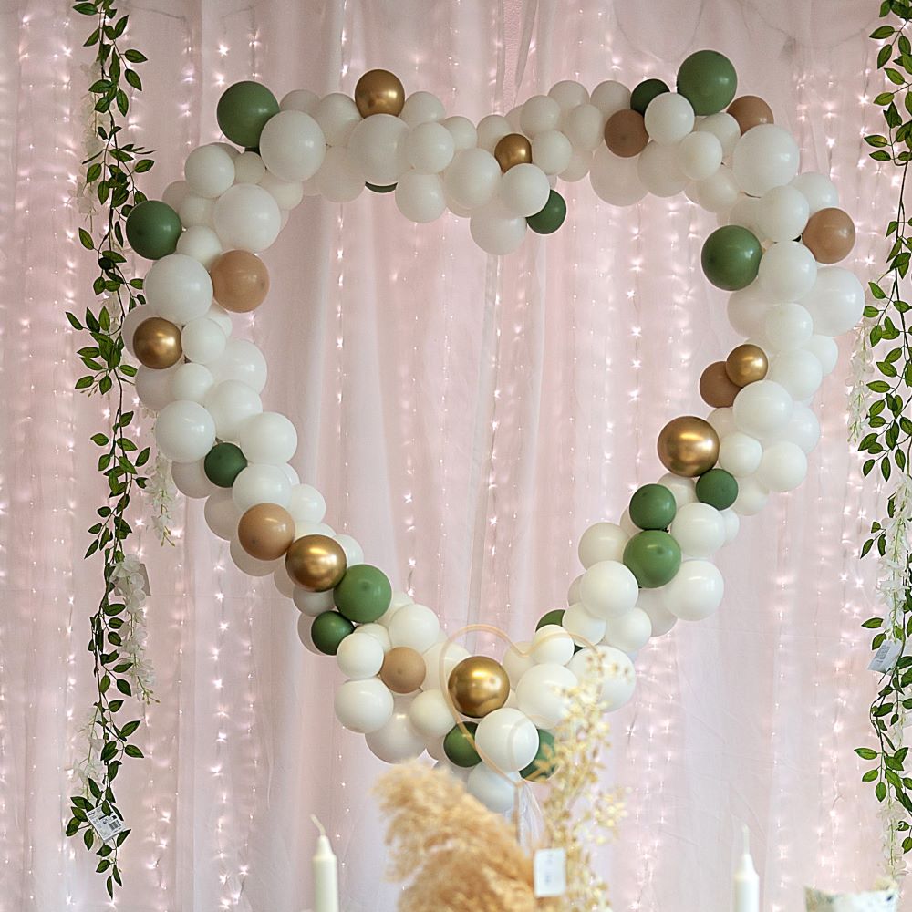 Herzförmige Ballondekoration aus Luftballons in verschiedenen Farben, gefüllt mit kleinen und großen Ballons, teilweise mit Metallic-Effekt, dekoriert auf einem Gestell, mittig mit Schriftzug „Mr & Mrs“ weiß grün