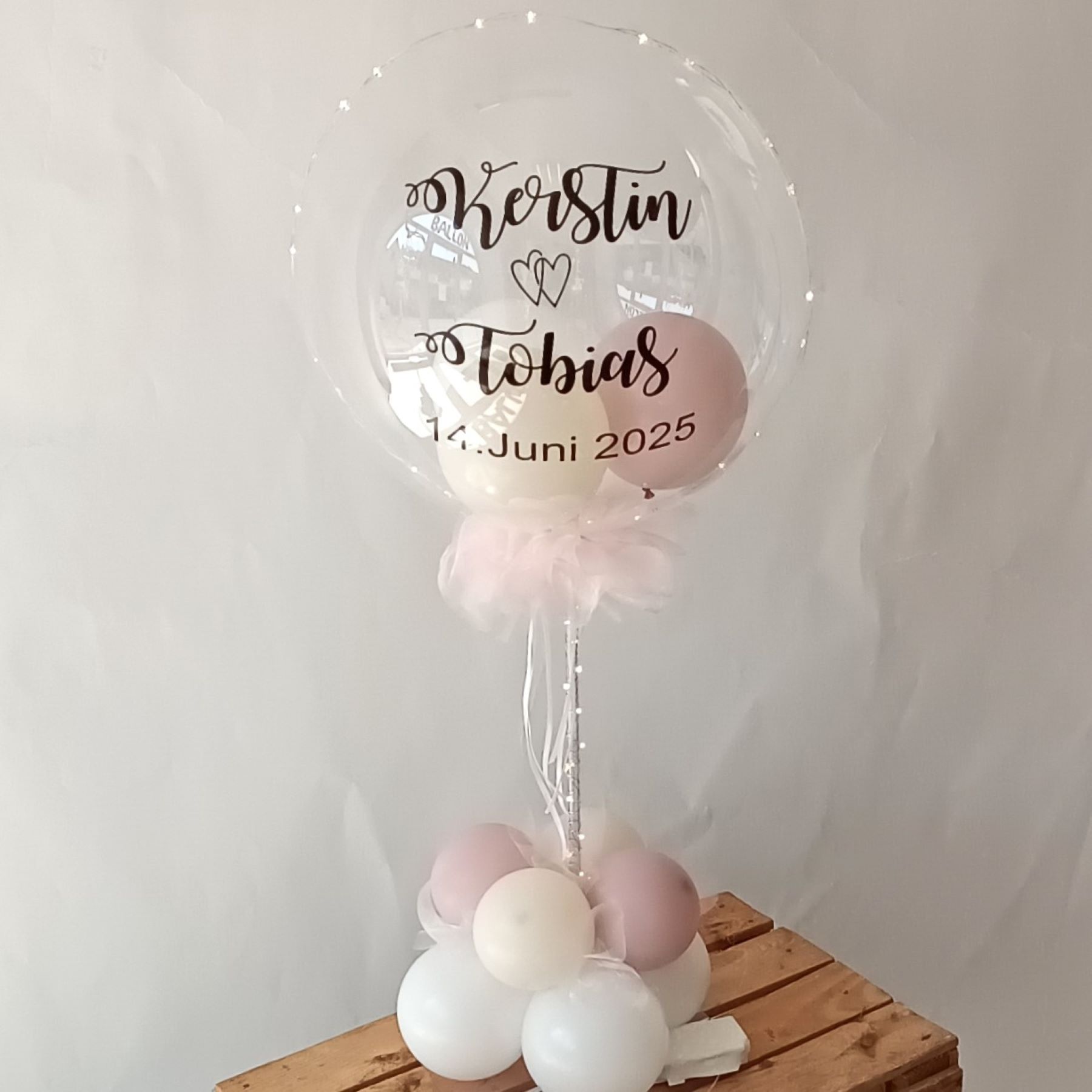 Transparenter Ballon auf Tischständer mit Namen 'Kerstin & Tobias' und Hochzeitsdatum, rosa-weiße Ballons.