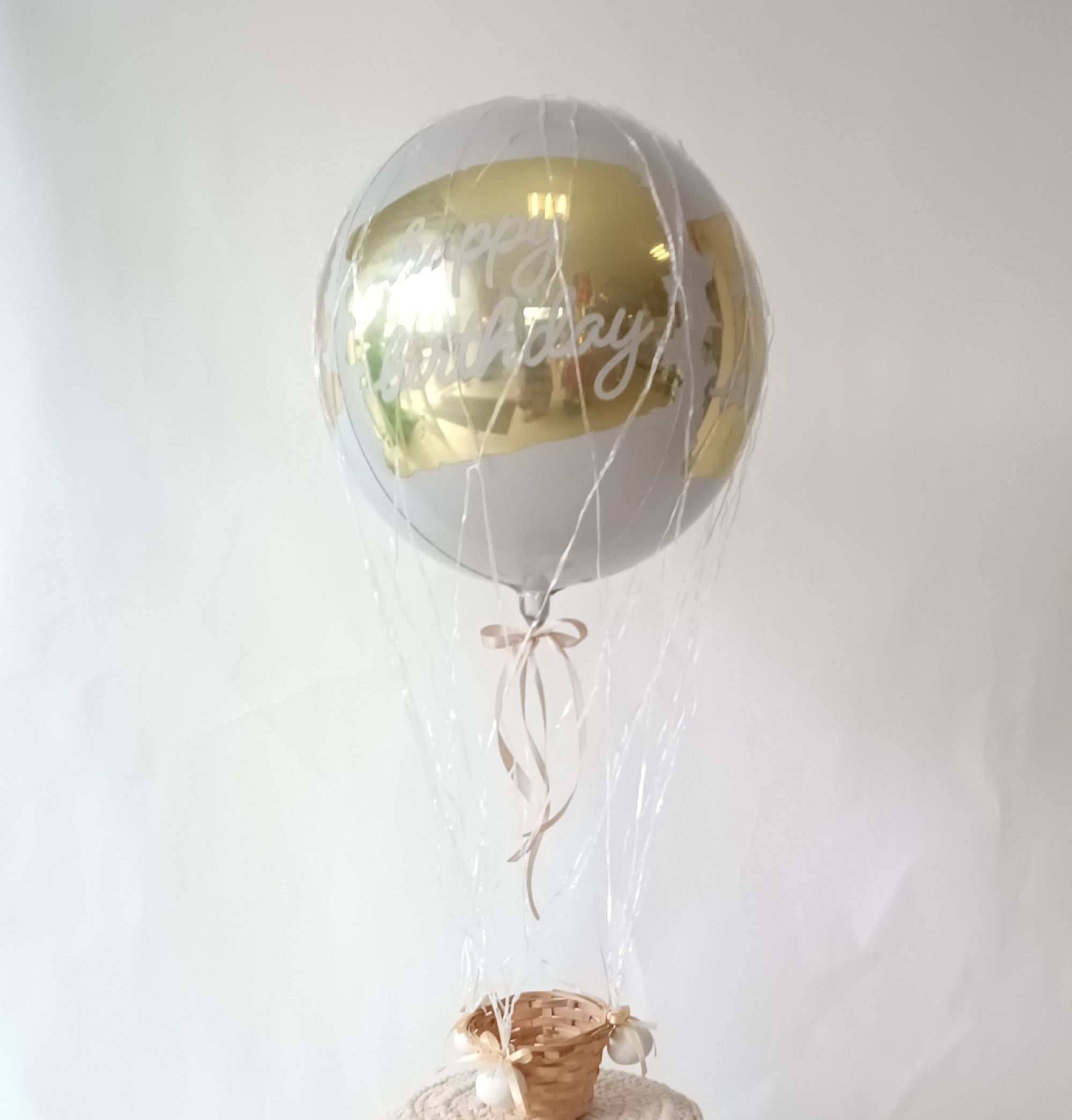 Ballon in Heißluftballon-Optik mit goldener Aufschrift 'Happy Birthday', in Weiß und Gold mit kleinem Körbchen.