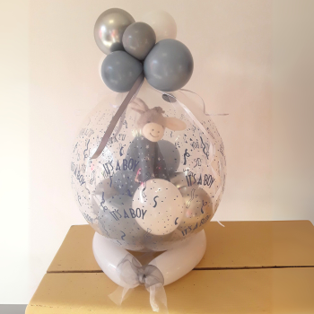 Transparenter Ballon mit blauer Aufschrift 'It's a Boy', dekoriert und gefüllt mit kleinen blauen und weißen Ballons und Esel-Plüschtier