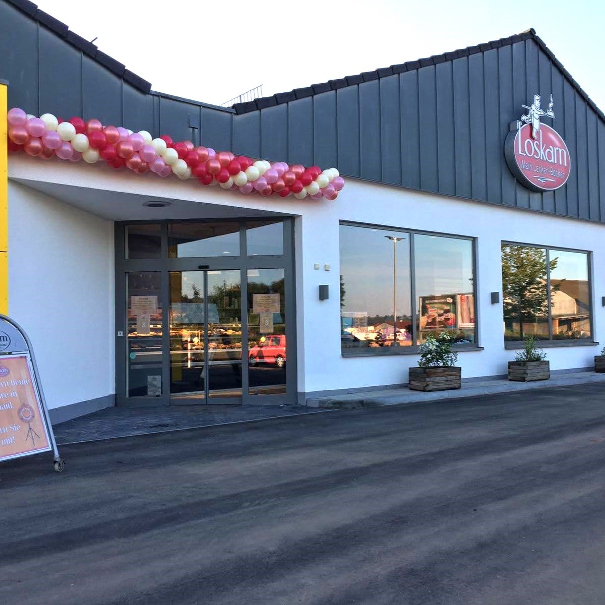 rot-weiß-rosa Ballongirlande über dem Eingang der Bäckerei Loskarn