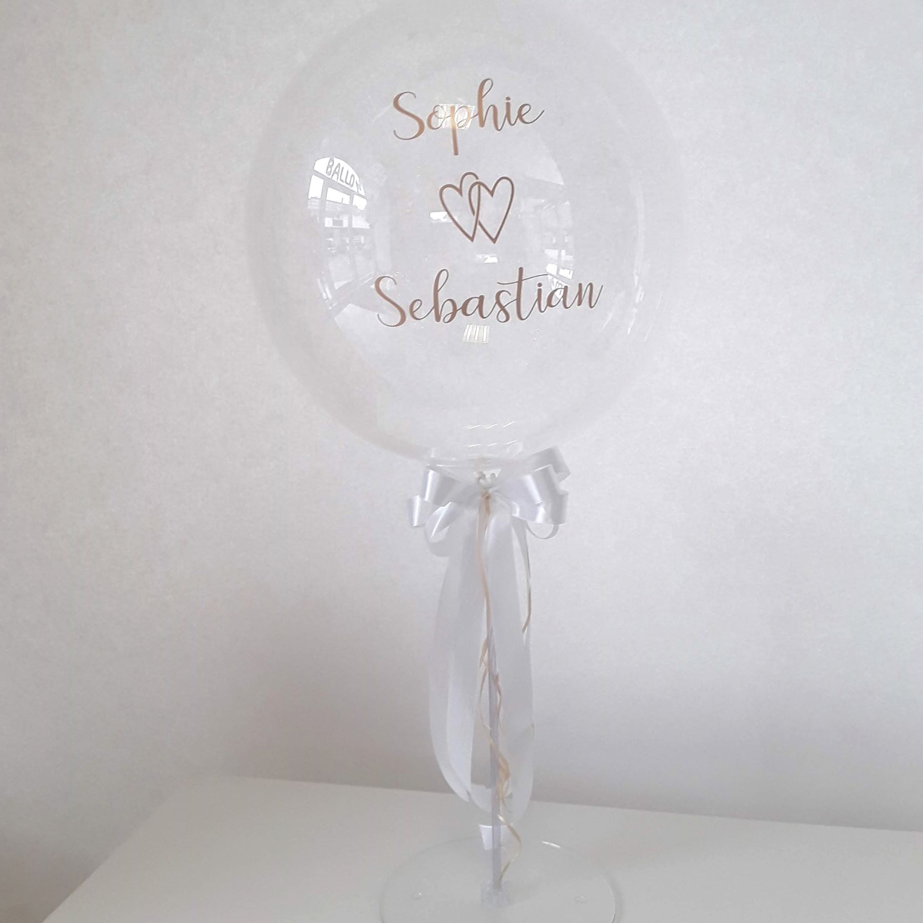 Transparenter Hochzeitsballon mit Namen 'Sophie & Sebastian', Tischständer mit Schleife in Weiß