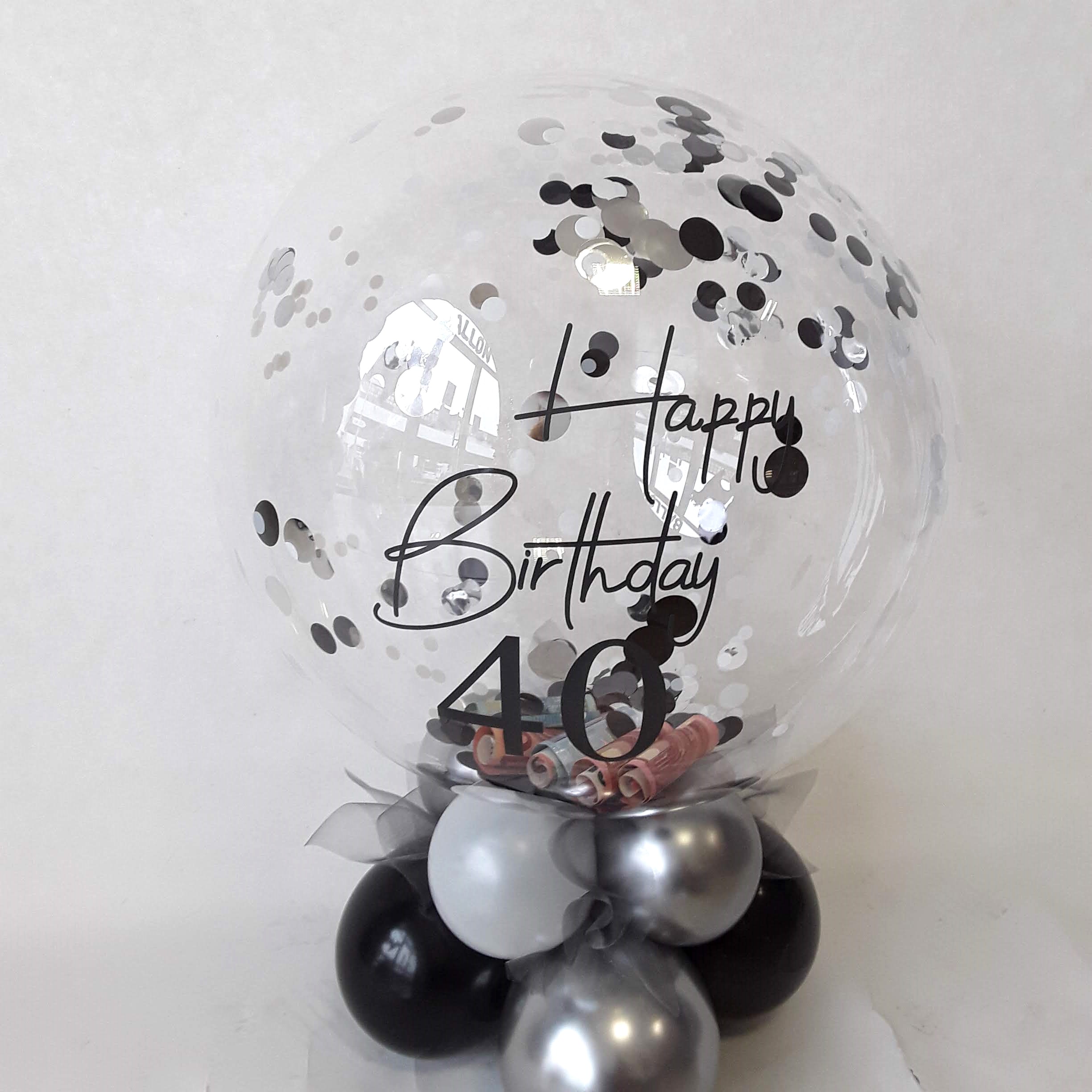 Transparenter Ballon mit schwarz-silbernem Konfetti und Geldscheinen, 'Happy Birthday 40'-Aufdruck und schwarz-weiß-silberner Ballonbasis