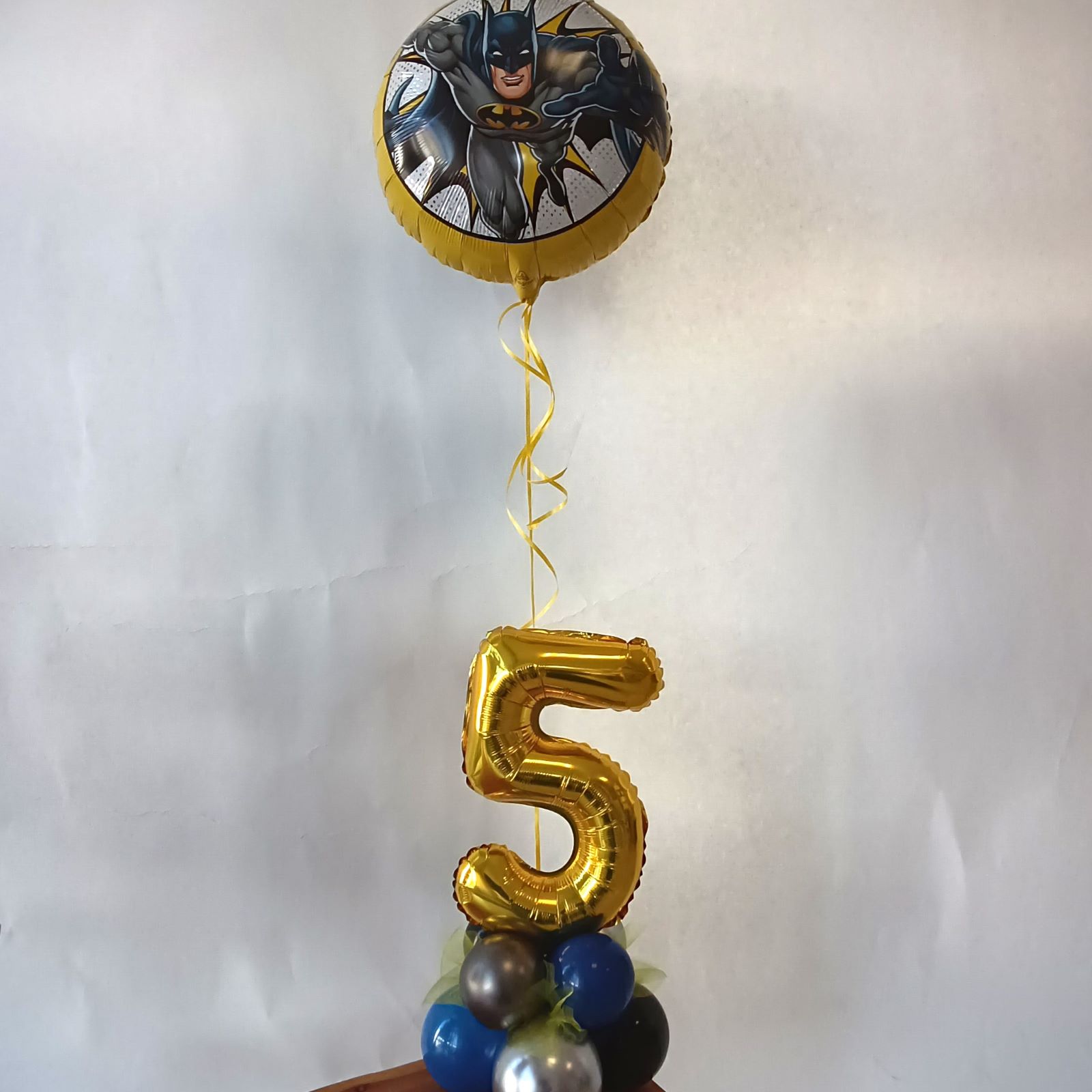 Ballondeko mit Batman-Folienballon, goldener Zahl 5 und Ballonbasis in Blau, Gold und Schwarz.