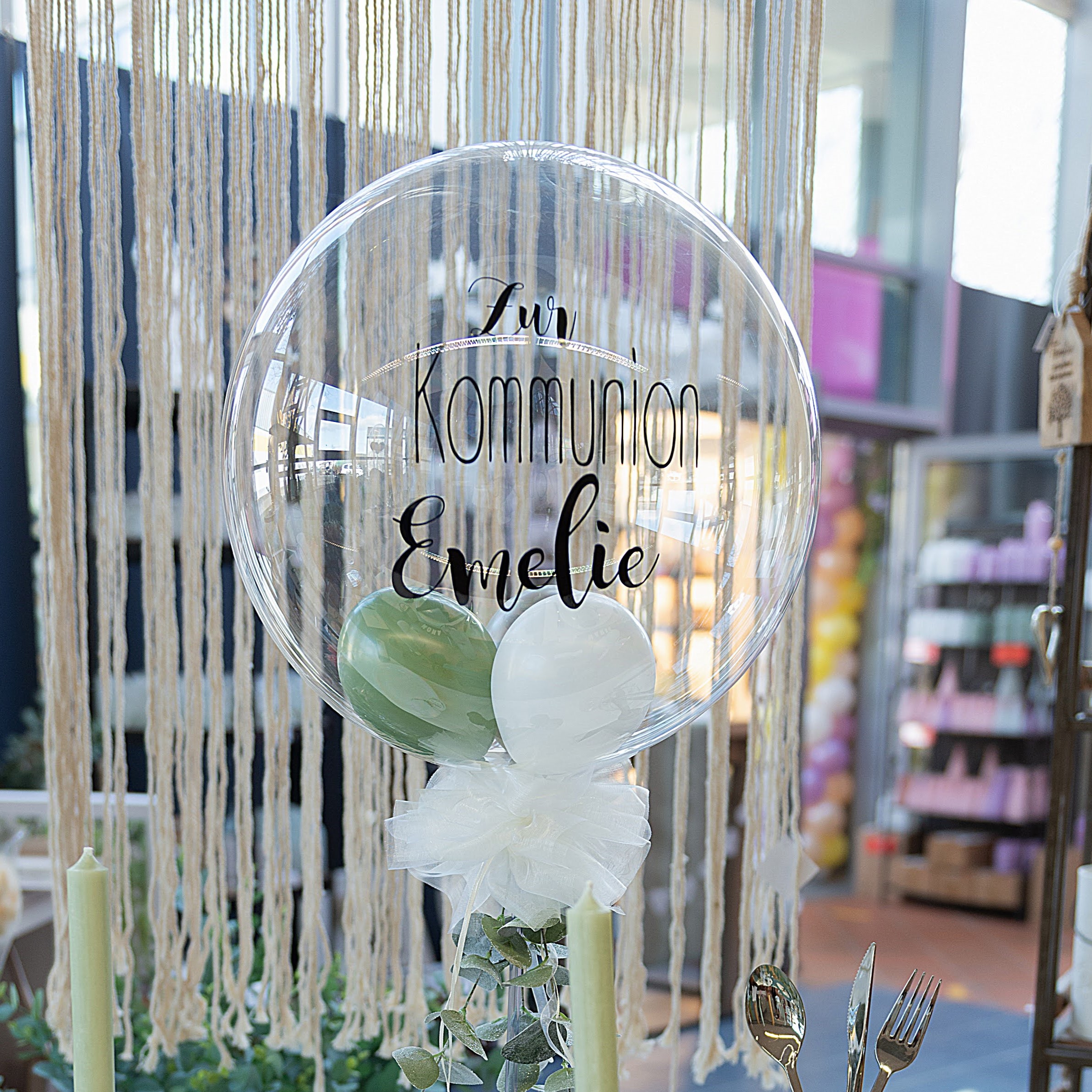 Tischständer mit Bubbleballon in Grün und Weiß, personalisiertem Aufdruck und Blätterdeko mit Name Emelie