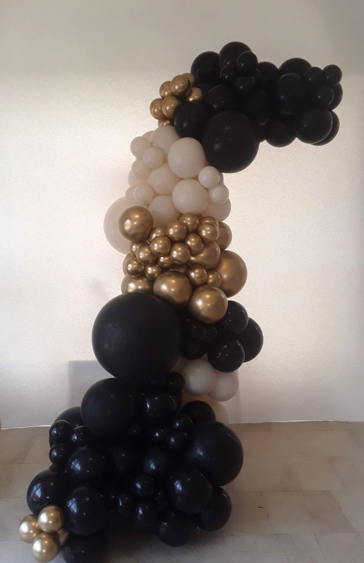 Halbkreisbogen aus schwarzen, goldenen und champagnerfarbenen Ballons in verschiedenen Größen