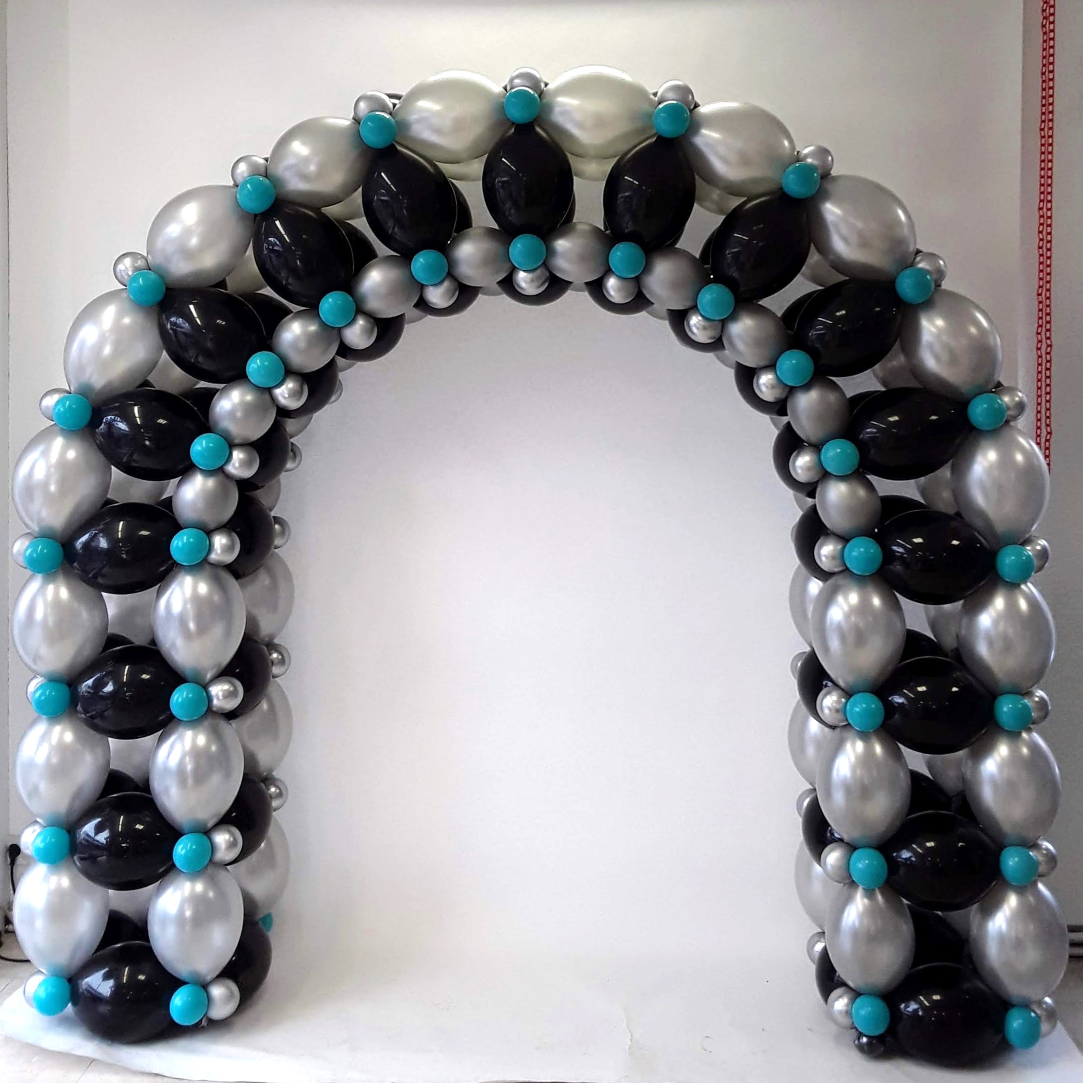 Ballonbogen in Schwarz, Silber und Türkis vor weißer Wand