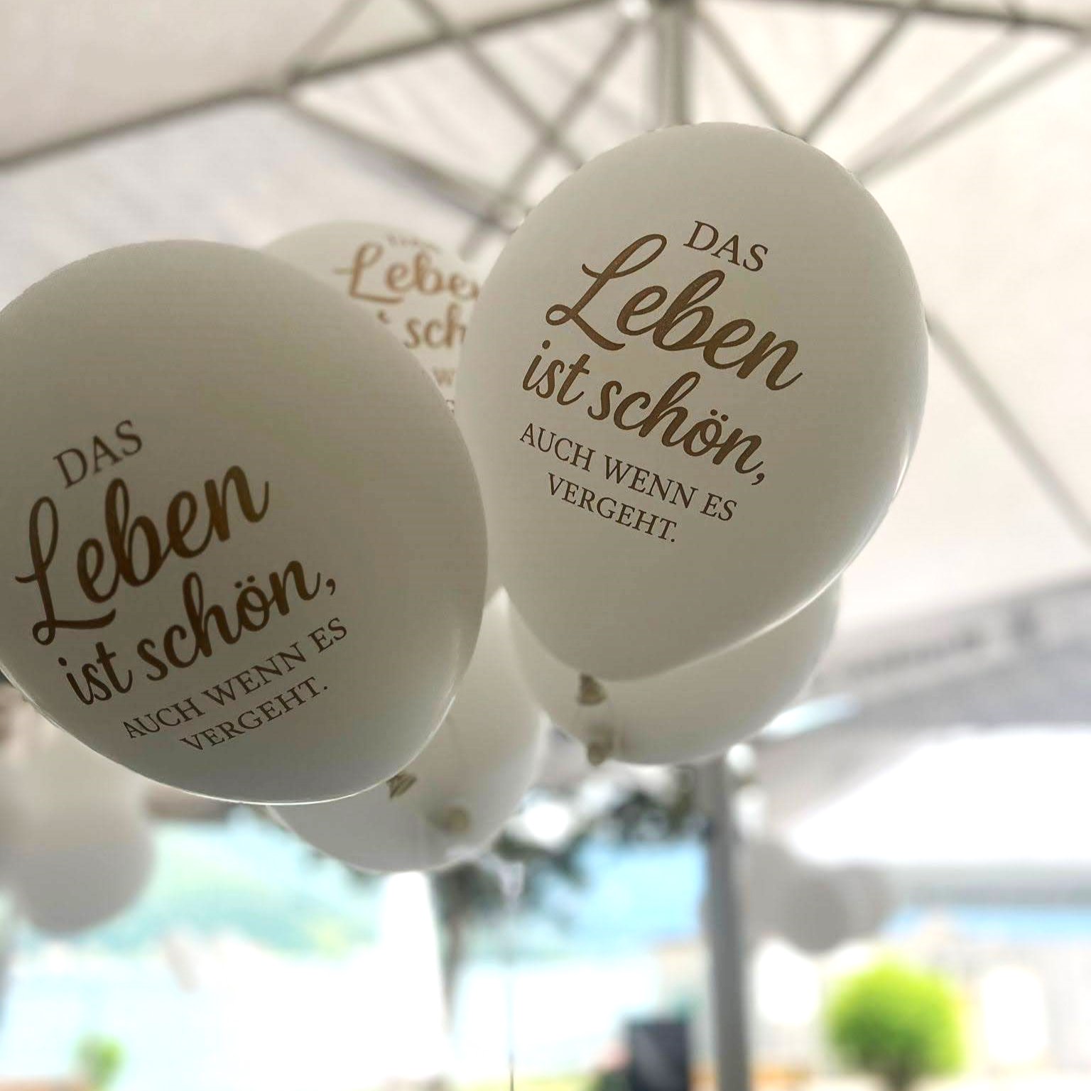 Weiße Latexballons mit dem Aufdruck 'Das Leben ist schön, auch wenn es vergeht.' – ideal für Trauerfeiern und Gedenkzeremonien.
