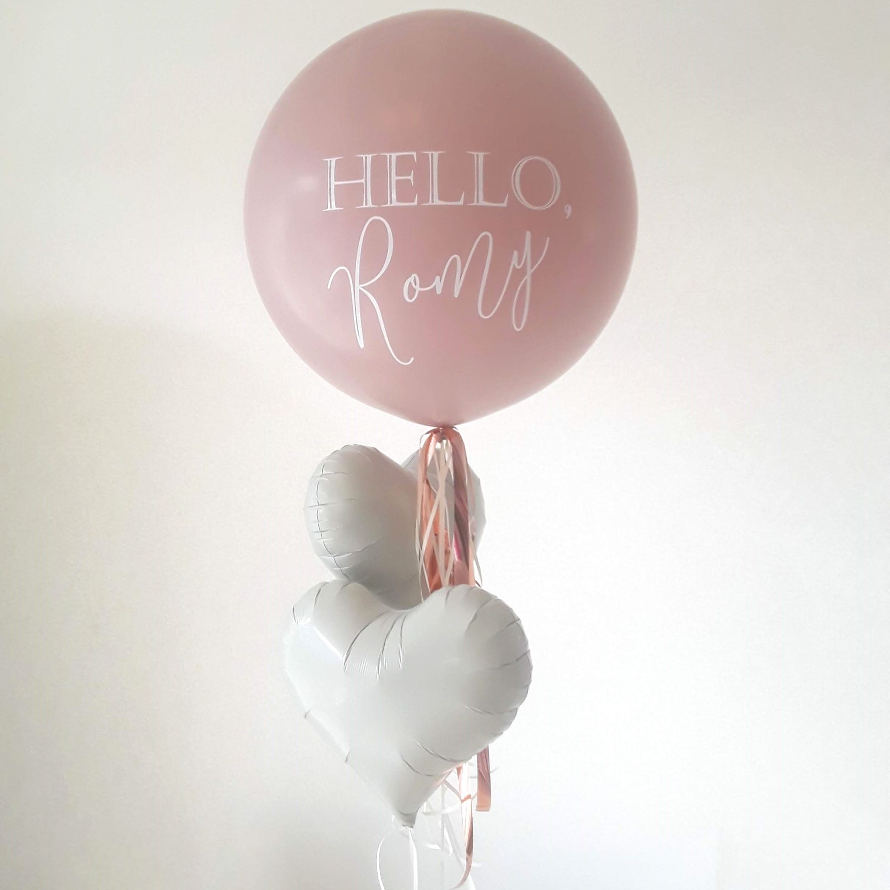 Rosa Ballon mit Aufdruck 'Hello Romy' und zwei weißen Herz-Folienballons'Hello Romy' und zwei weißen Herzballons