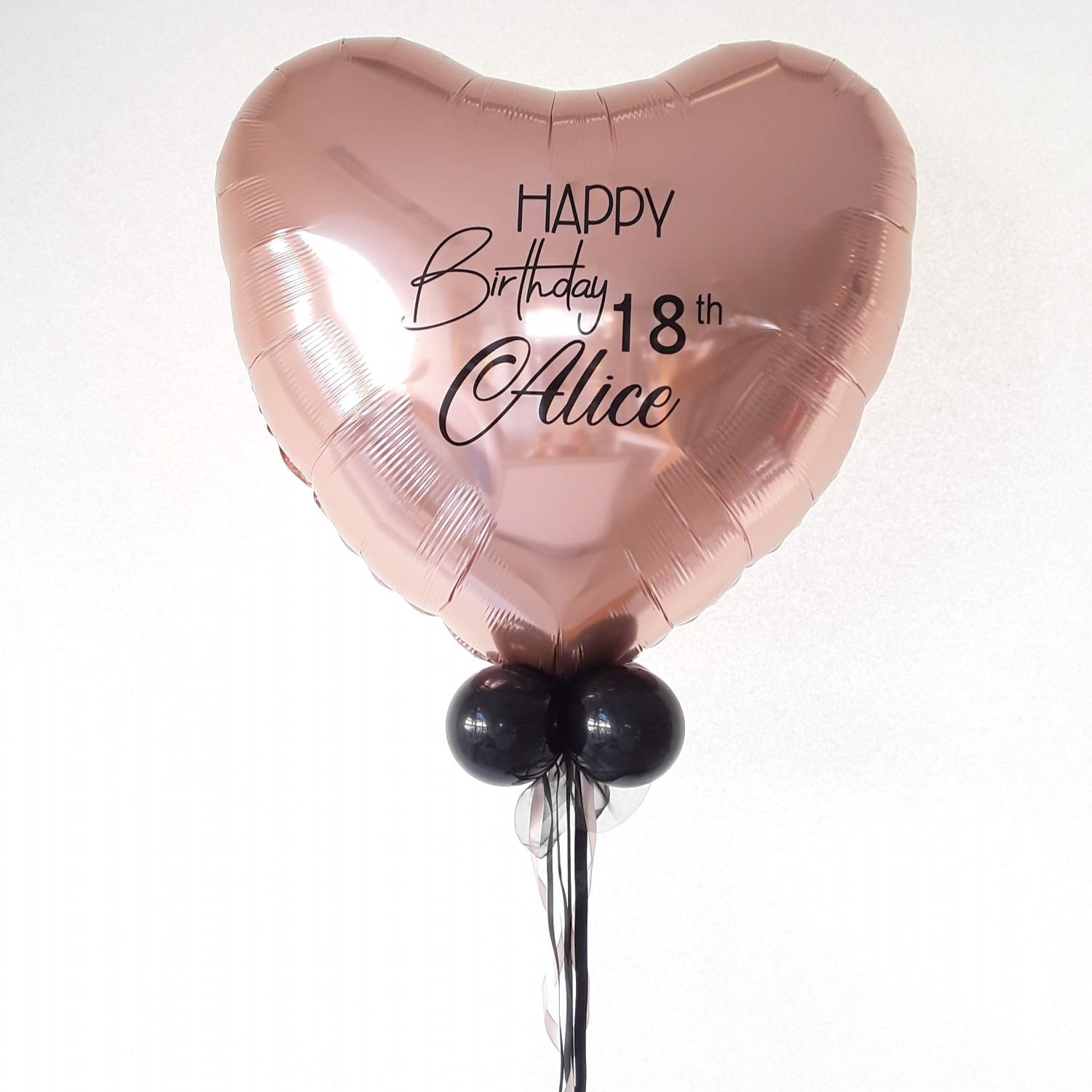 Herzballon in Rosé mit schwarzem Aufdruck 'Alice', dekoriert mit kleiner Schleife und kleinen schwarzen Luftballons