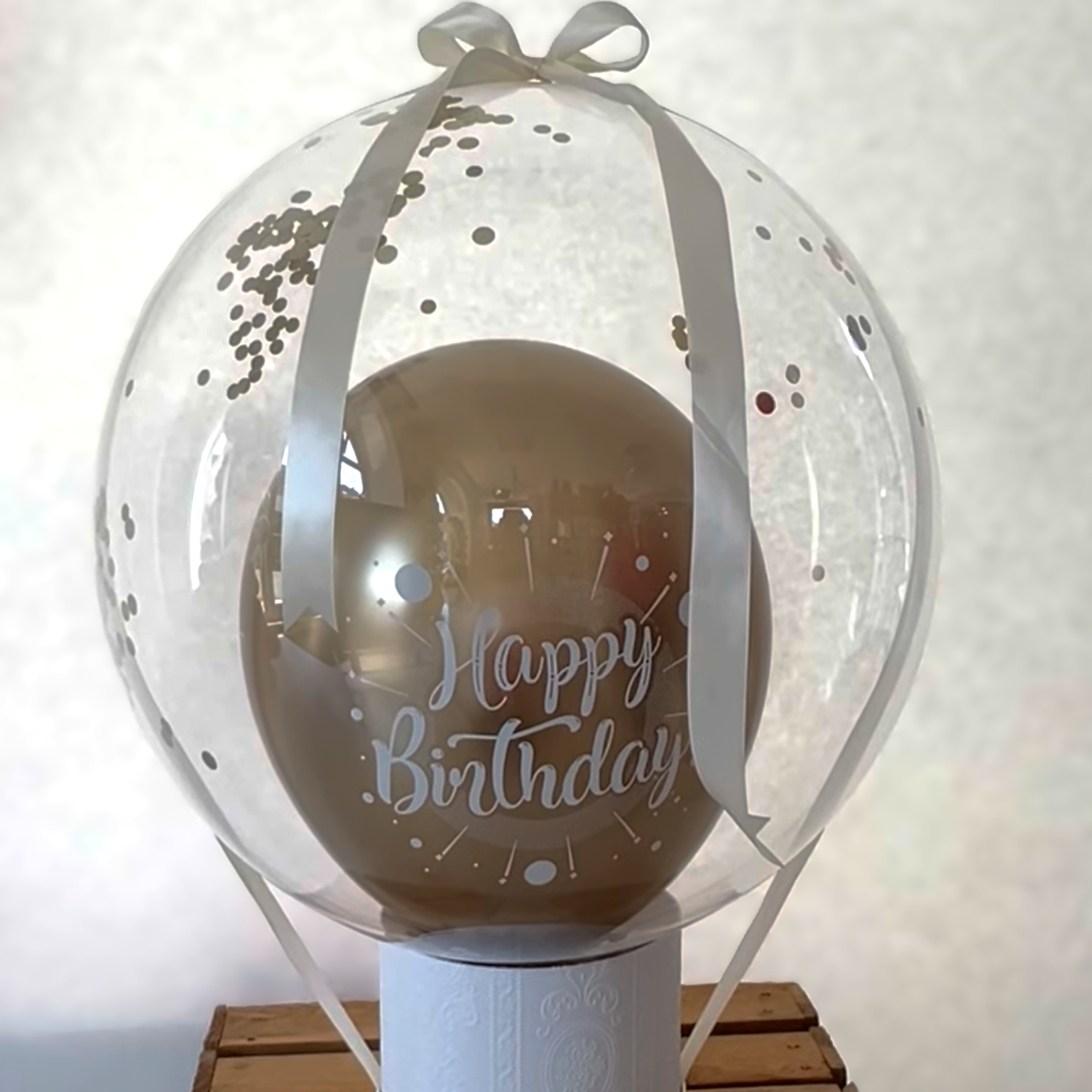 Transparenter Konfetti-Ballon auf Sockel mit Geldscheinen als kreatives Geldgeschenk Foto