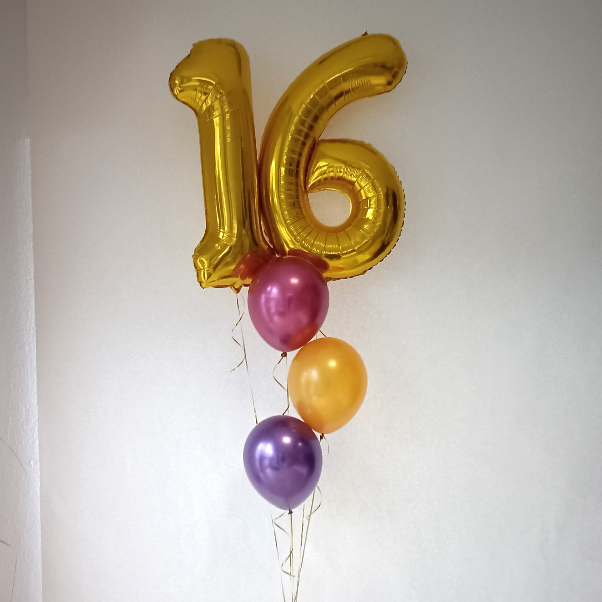 Goldene Folienballons in Form der Zahlen 1 und 6 mit pinken, goldenen und violetten Latexballons.