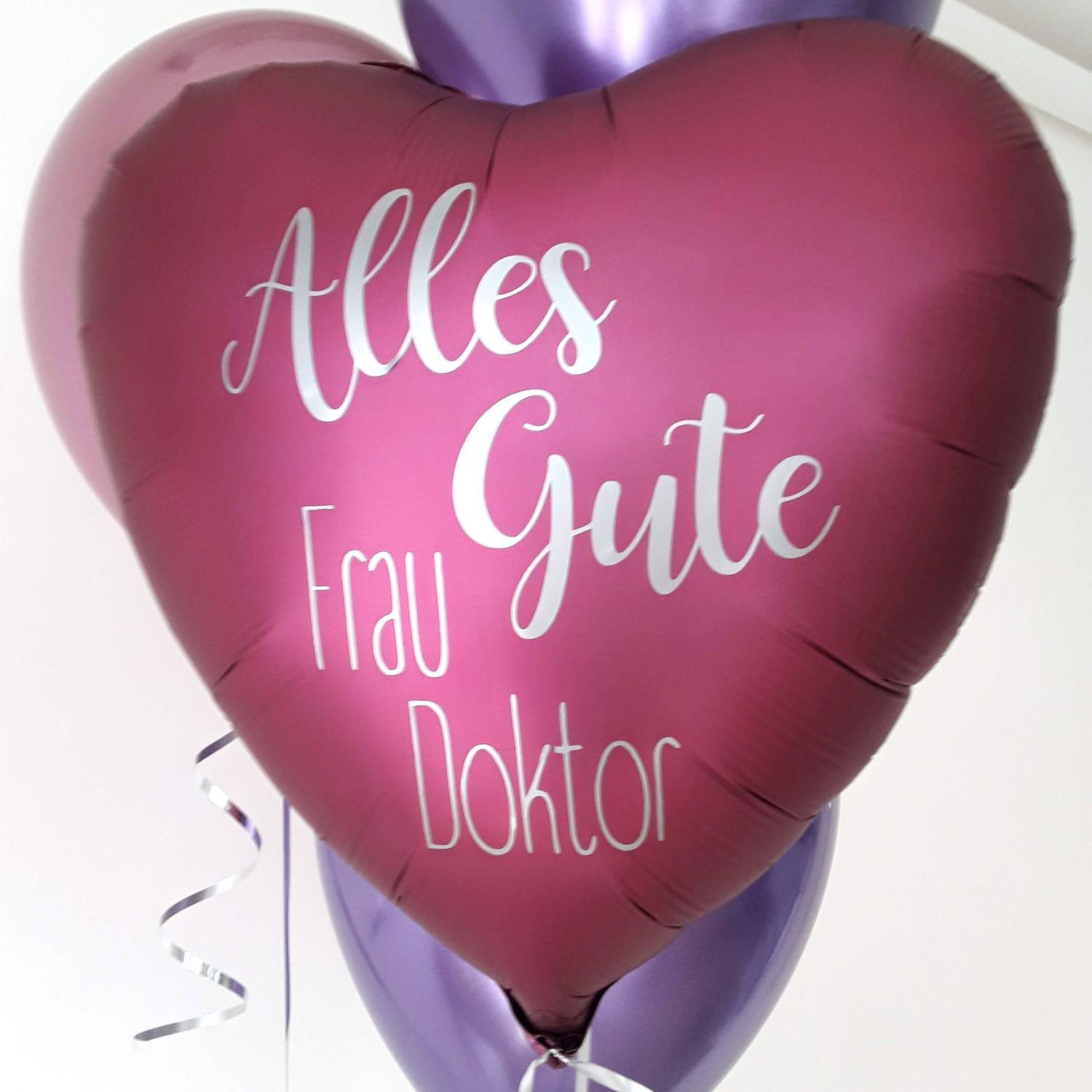 Herzförmiger Folienballon in Pink mit weißem Aufdruck 'Alles Gute Frau Doktor'