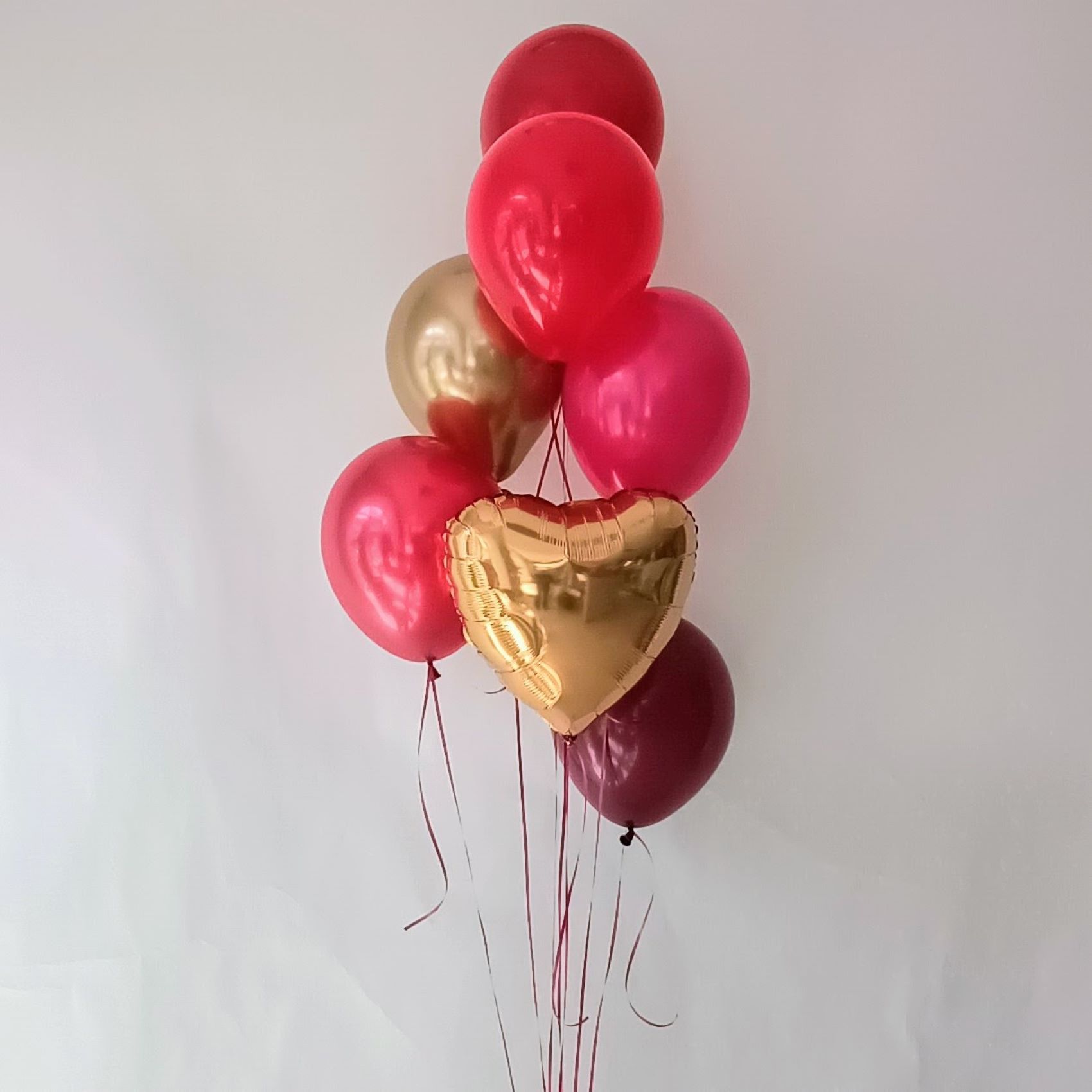 Ballonbouquet mit Latexballons in Pink, Rot und Gold sowie einem goldenen Folienballon in Herzform