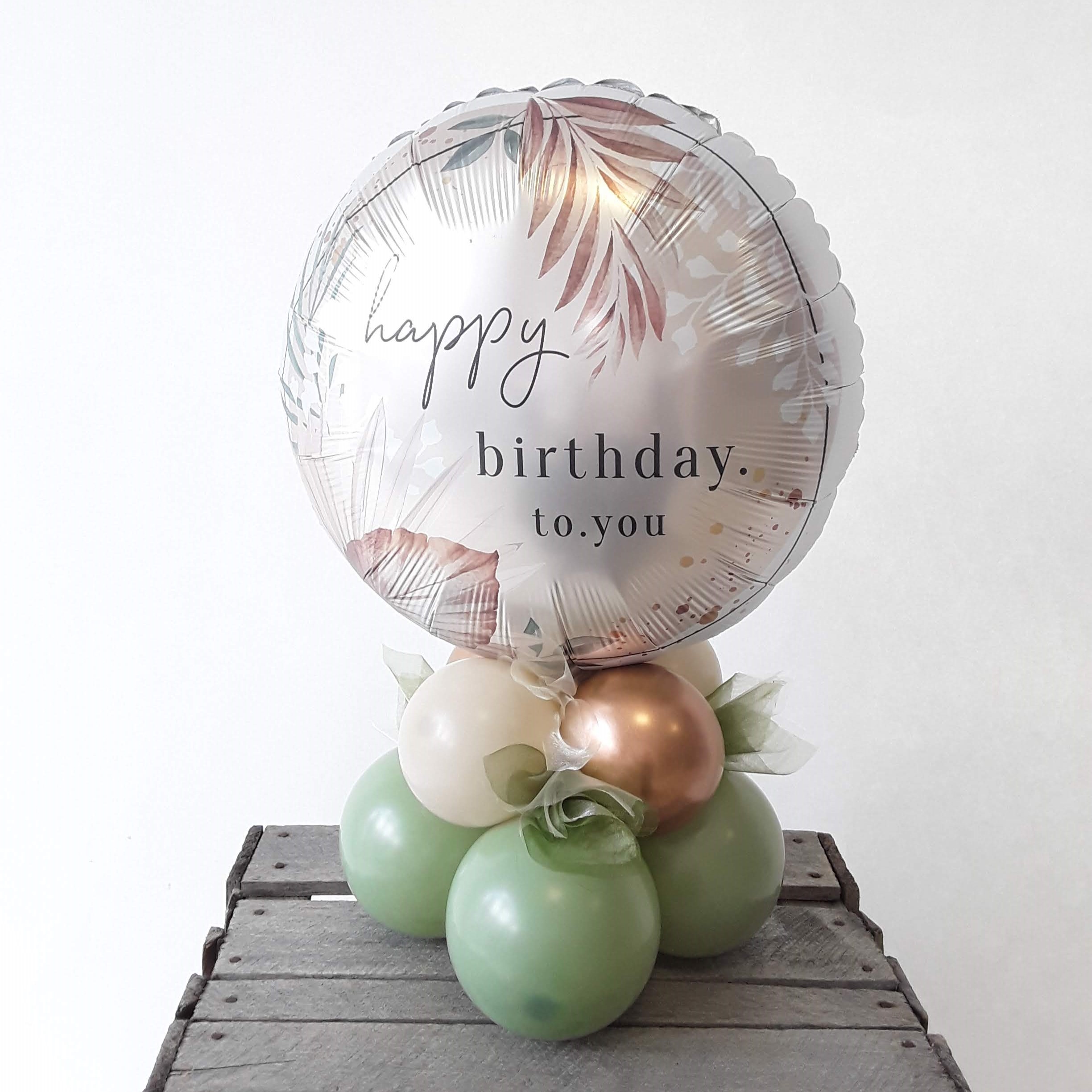 Grüner Folienballon mit Happy Birthday Aufdruck in Bronze, dekorativ als Tischbouquet arrangiert.