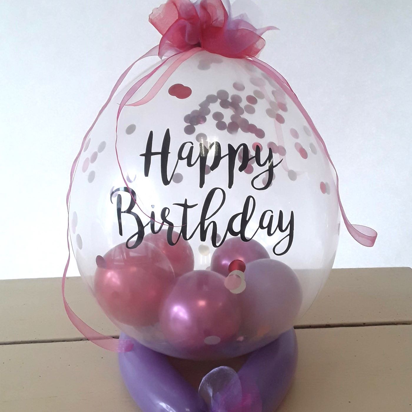 Bubble-Ballon Happy Birthday gefüllt mit rosa und violetten Ballons, Konfetti, Schleife