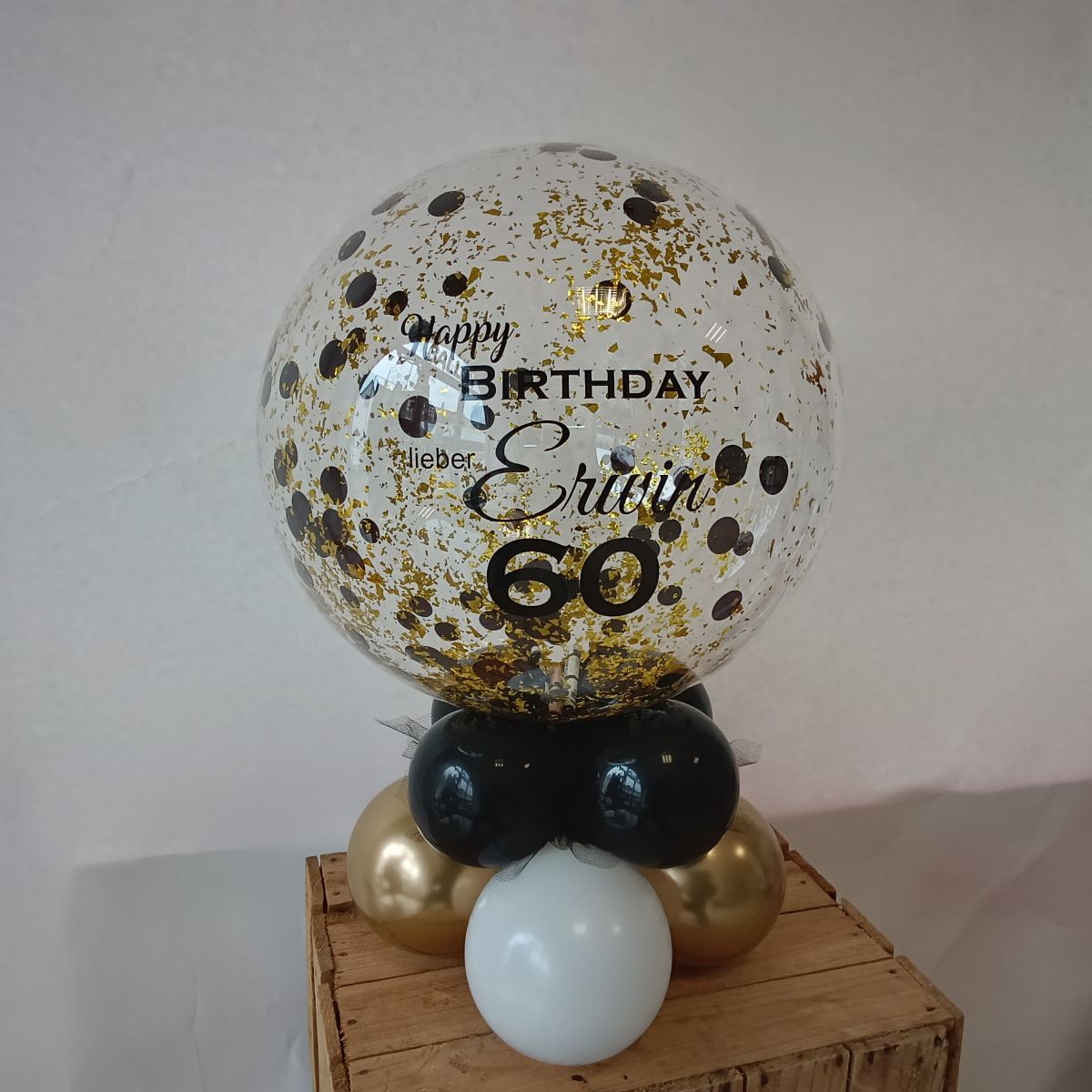 Transparente Ballonkugel mit schwarzem und goldenem Konfetti, personalisiert mit Aufdruck 'Happy Birthday lieber Erwin 60', auf schwarz-gold-weißer Basis