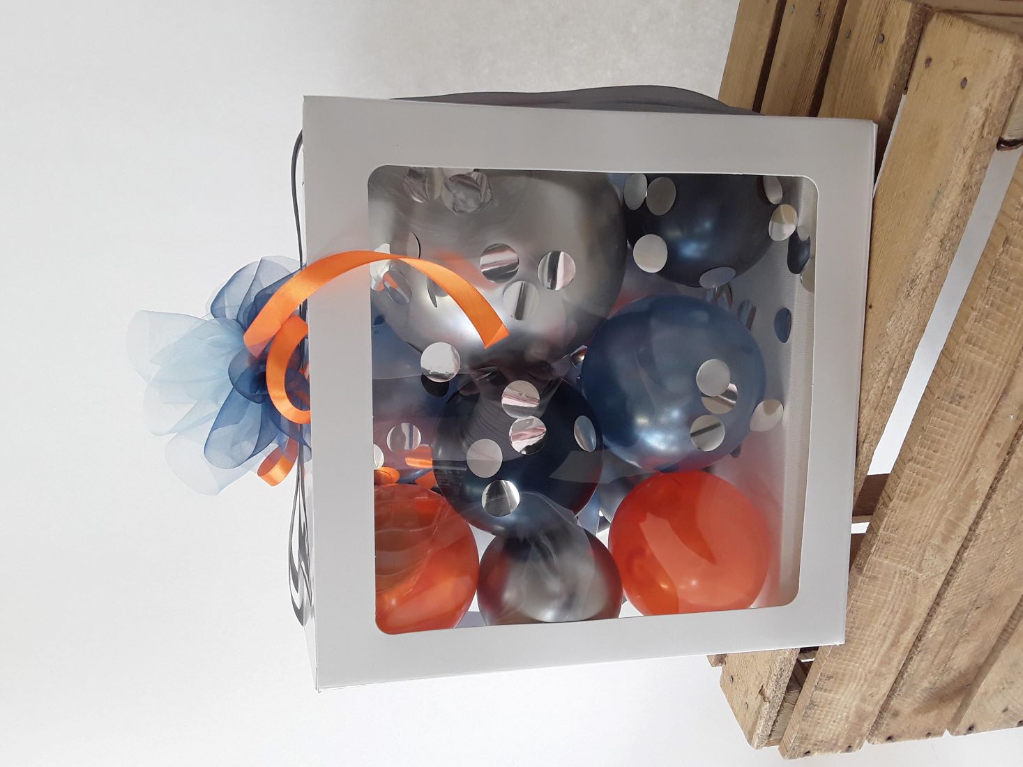 Ballonbox, gefüllt mit Ballons in Blau, Silber und Orange, Schleife in Blau