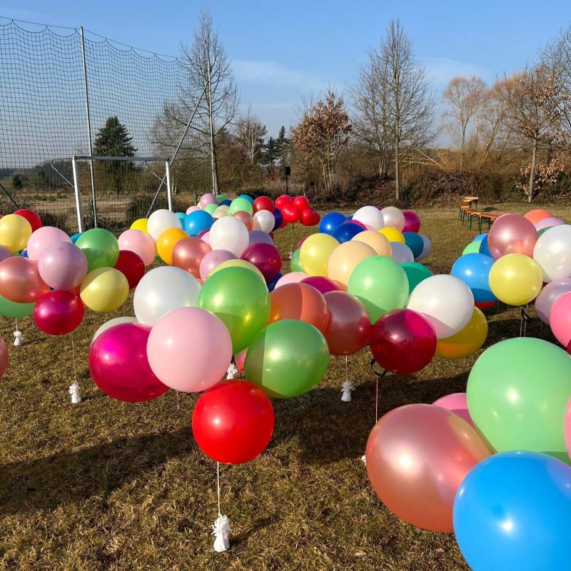 Bunte Latexballons in vielen Farben hängen unter einer Decke, alle mit Schnüren versehen-5