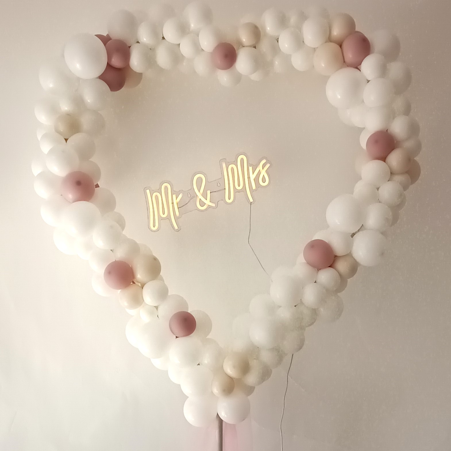 Herzförmige Ballondekoration aus Luftballons in verschiedenen Farben, gefüllt mit kleinen und großen Ballons, teilweise mit Metallic-Effekt, dekoriert auf einem Gestell, mittig mit Schriftzug „Mr & Mrs“ weiss rosa2