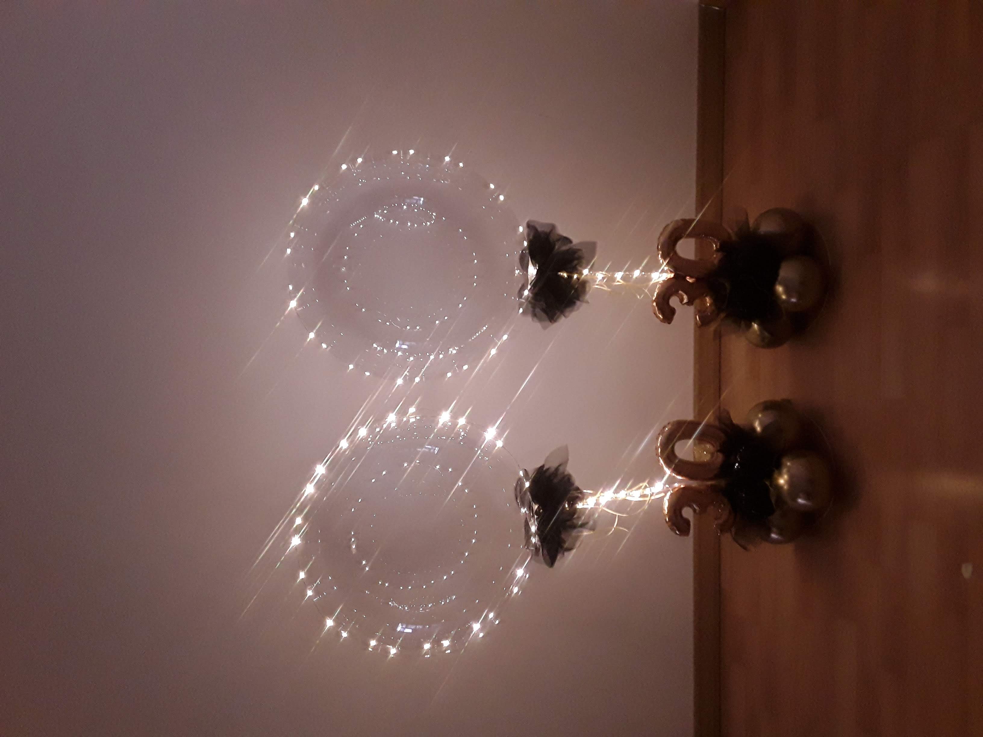 Zwei Tischständer mit je Transparenter Ballon mit Lichterkette, schwarze Schleife, goldene 30 auf Ballonbasis, im Dunkeln und leuchtender Lichterkette  fotografiert