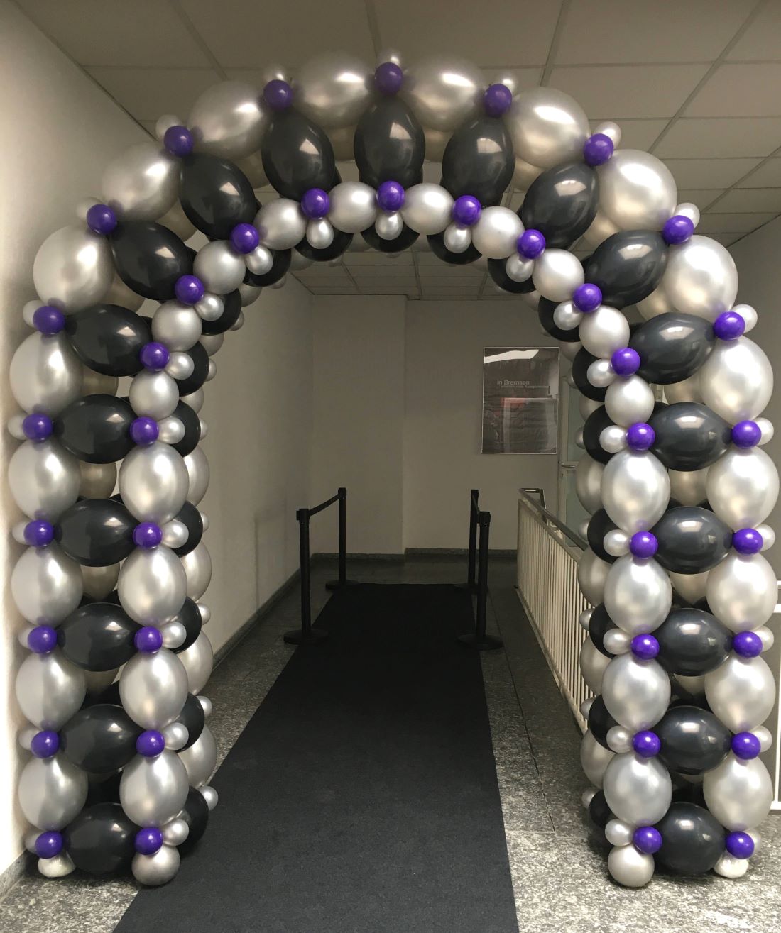 Ballonbogen in schwarz, silber, lila im Flur eines Gebäudes