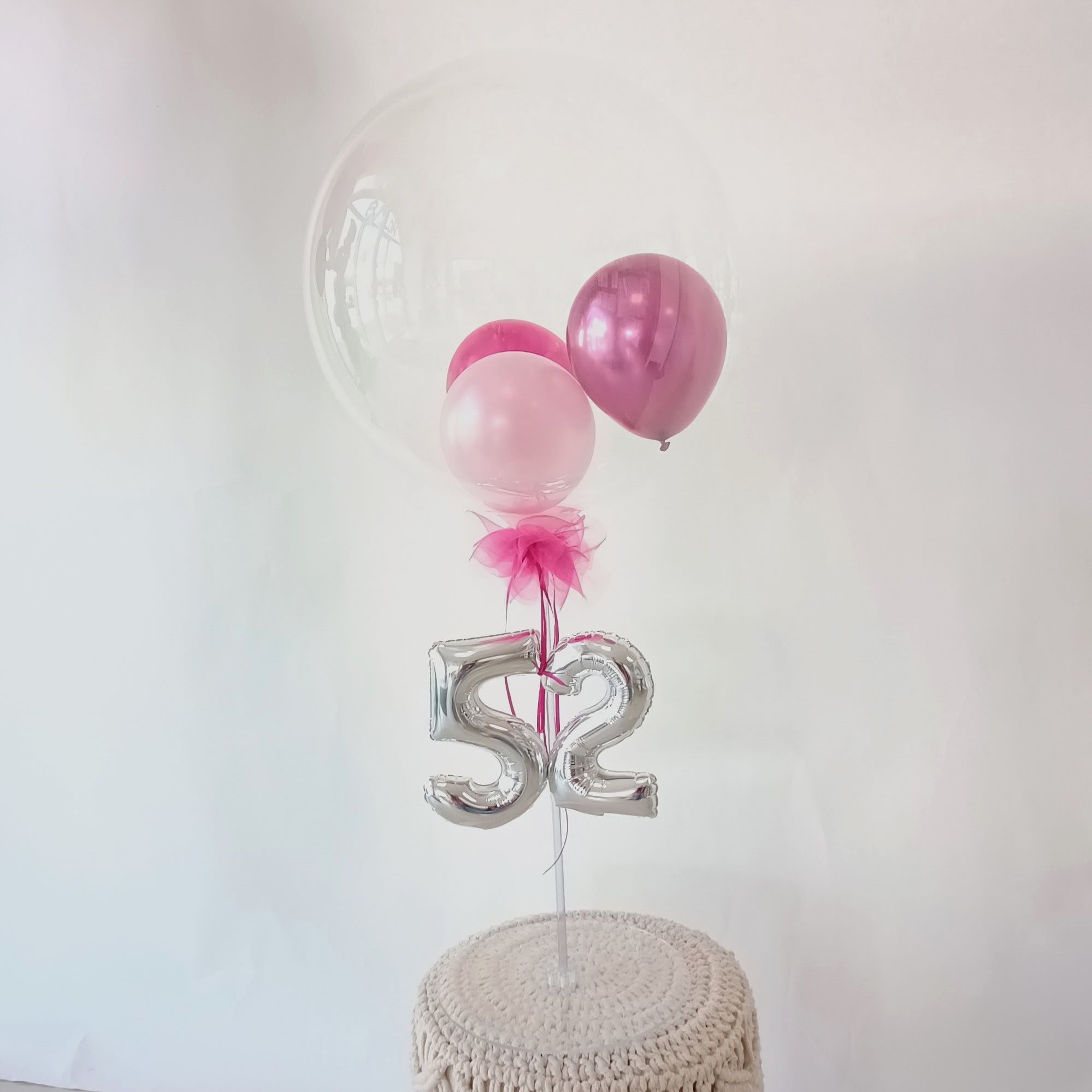 Ballonständer mit durchsichtiger Hülle, pinken Luftballons und silberner Zahl 52