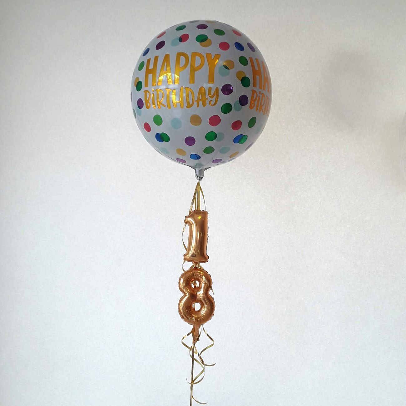 Bunter Ballon mit Aufdruck 'Happy Birthday' und kleinen goldenen Zahlenballons '1' und '8'