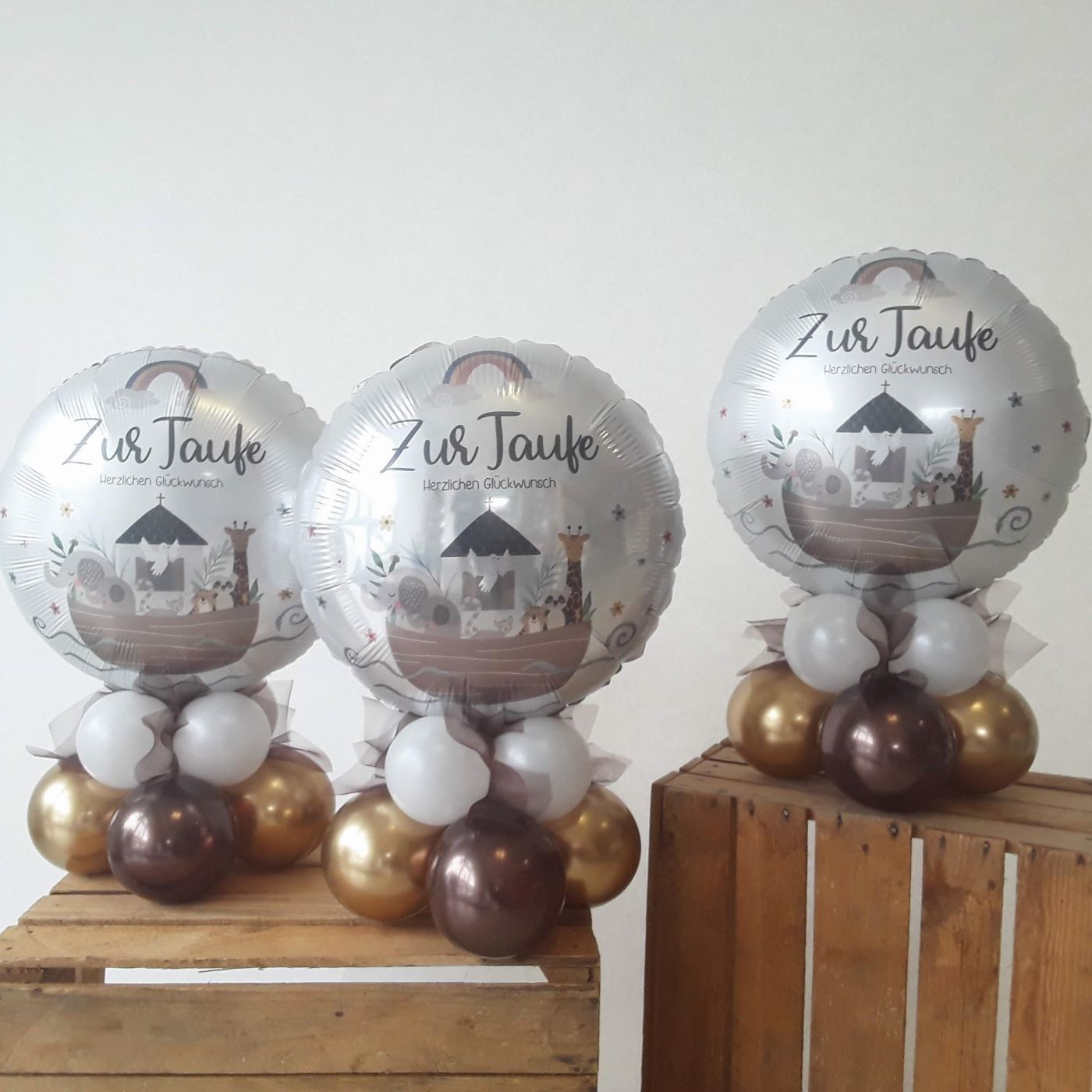 Silberner runder Folienballon mit Aufdruck 'Zur Taufe – Herzlichen Glückwunsch' und Arche Noah Motiv, auf Basis aus goldenen und weißen Luftballons.