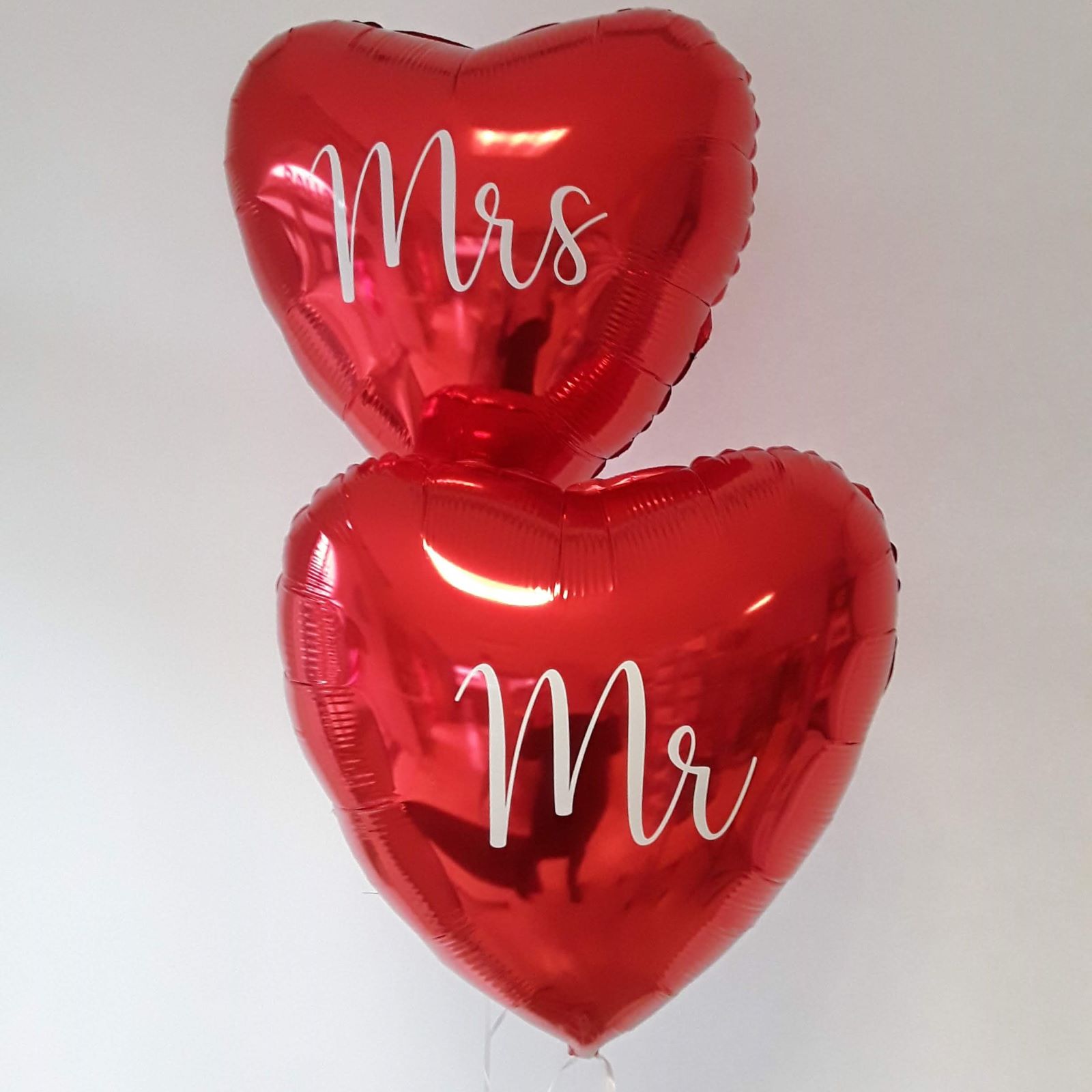 Zwei rote Folienballons in Herzform mit Aufdruck 'Mr' und 'Mrs'